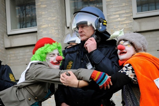 Climate change demonstrators dressed as clowns hug a police officer outside the Danish Foreign Ministry while demonstrators pass during the climate march in Copenhagen on December 12, 2009. At least 30,000 people marched through Copenhagen, demanding world leaders declare war on the greenhouse gases that threaten future generations with hunger, poverty and homelessness. If all goes well, the 194-nation conference under the UN's Framework Convention on Climate Change (UNFCCC) will wrap up on December 18 with a historic deal sealed by more than 110 heads of state and government.   TOPSHOTS/ AFP PHOTO/  ADRIAN DENNIS (Photo credit should read ADRIAN DENNIS/ AFP/ Getty Images)